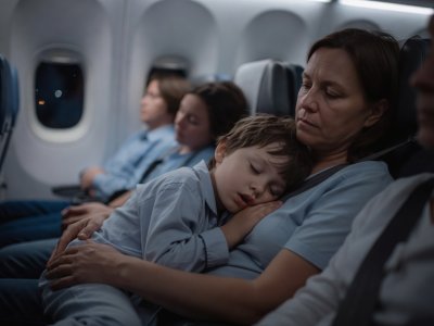 Child sleeping on a parent's shoulder during a flight